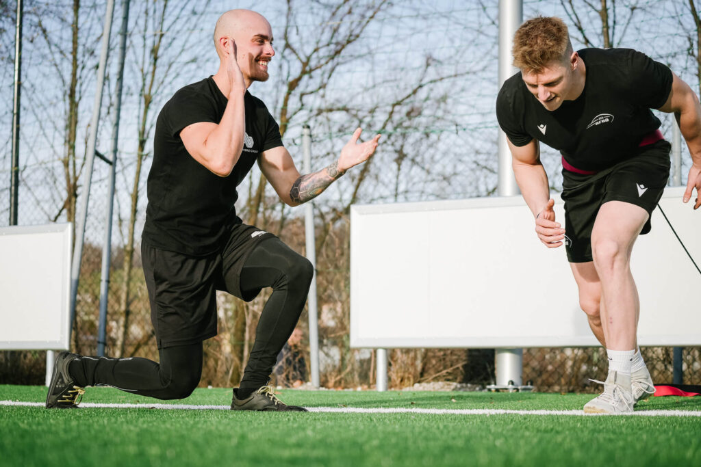 Personal Trainer feuert Trainierenden beim Sprinttraining auf Outdoorfläche an