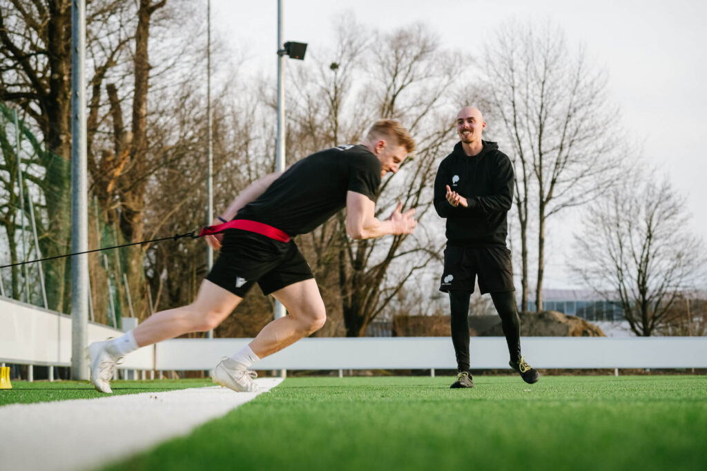 Personal Trainer feuert Trainierenden beim Sprinttraining auf Outdoorfläche an