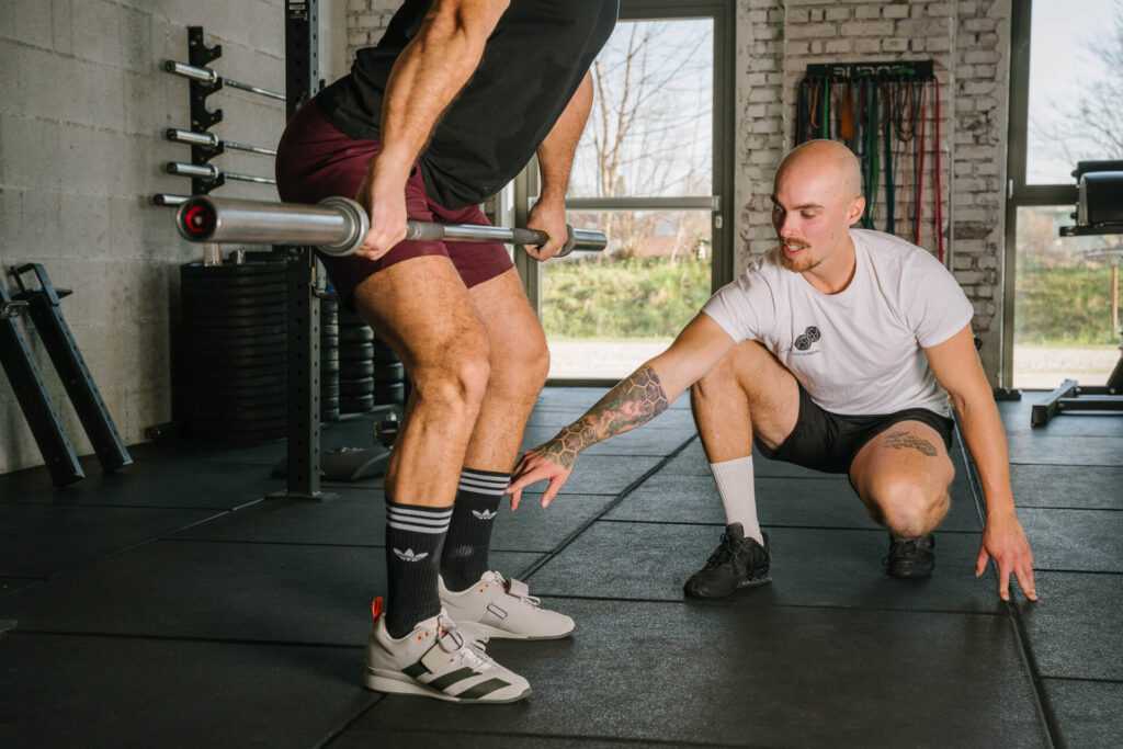 Personal Trainer gibt Kunde Anweisungen im Fitnessstudio