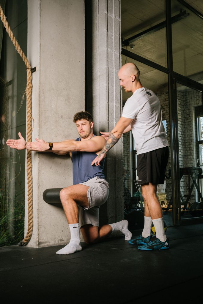 Personal Coaching im Fitnessstudio an Wand mit Anweisungen durch Trainer